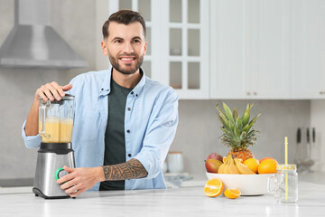 Poster - Handsome man preparing ingredients for tasty smoothie at white marble table in kitchen