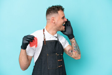 Wall Mural - Butcher caucasian man wearing an apron and serving fresh cut meat isolated on blue background shouting with mouth wide open to the side