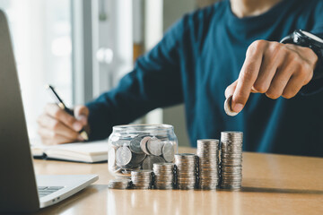 Wall Mural - Hand putting coins in a piggy bank for save money and Saving Money concept.