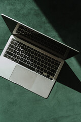 Wall Mural - laptop computer on green velours background with sunlight shadows