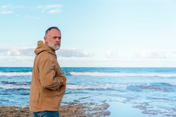 Wall Mural - Bearded Man relaxing alone on the seaside on hot sunny day at sunset. Travel  Lifestyle concept