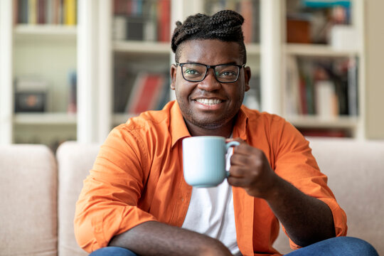 Wall Mural - Happy young black man enjoying morning coffee at home