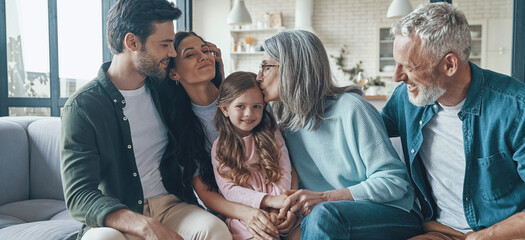 Happy multi-generation family bonding while sitting on the sofa at home together