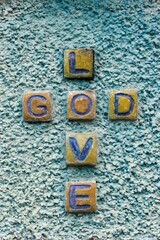 Sticker - Stone graved text crossing of GOD LOVE on rough texture wall, vertical shot