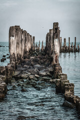 Wall Mural - Old ruined wooden pier and a sandy beach