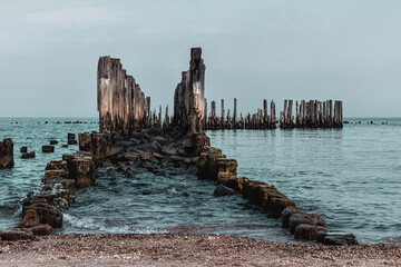 Wall Mural - Old ruined wooden pier and a sandy beach