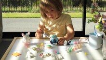 A Cute Little Girl Is Decorating An Easter Egg. Ideas Of Easter Crafts 