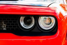 Close Up Of Headlight Detail Of Modern Luxury Sportscar With Reflection On Red Paint. Front View Of Supercar. Concept Of Car Detailing And Paint Protection Background.