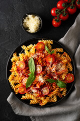 Wall Mural - Fusilli pasta with tomatoes, basil, parmesan, and sauce on back background