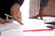 © NT_studio - Closeup hands young caucasian architect woman looking laptop and working drawing blueprint for planning building house, engineer thinking and sketching blueprint for construction, industry concept.