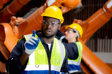 Two young engineer man checking and maintenance machine robot arms technology intelligence and innovation at factory industrial, people or technician examining robot, inspector and industry concept.