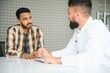 © Serhii - medicine, healthcare and people concept - happy doctor with clipboard and young male patient meeting at hospital