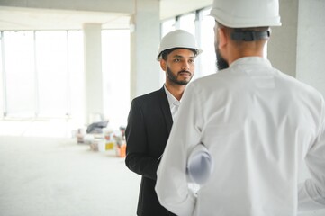 Wall Mural - Construction concept of multiracial Engineer and Architect working at Construction Site with blue print