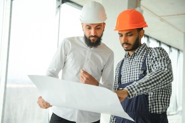 Wall Mural - Young attractive arabic industrial engineer in hard hat. Professional and industry, builder architect job, worker checking work at plant indoor