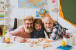 Father and son playing in school class. Child hugging young father and elderly grandfather. Happy smiling grandson boy with dad and granddad playing games together.