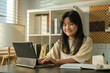 © wattana - Smiling female student doing homework or watching remote education online class on digital tablet in cozy sunny living room.