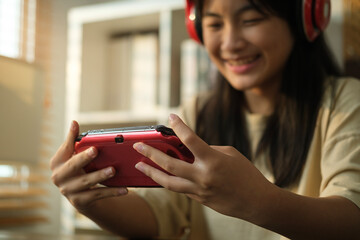 Cheerful teenage girl in headphone playing video game, spending leisure weekend time at home.