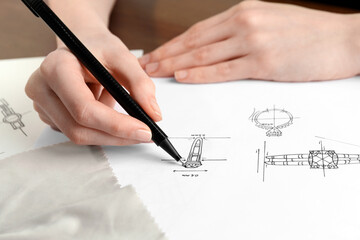 Wall Mural - Jeweler drawing sketch of elegant ring on paper at table, closeup