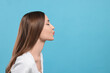 © New Africa - Beautiful young woman blowing kiss on light blue background, space for text