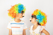© sorapop - April Fool's Day. Two brothers funny kid boy and little girl clown wears curly wig colorful big nos and glasses and has mustache isolated on white background, Happy children festive decor