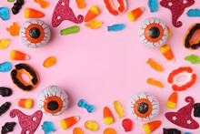 Frame Made Of Tasty Candies And Halloween Decorations On Pink Background, Flat Lay. Space For Text