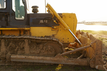 Yellow bulldozer with a metal bucket, close-up. Construction tractor on caterpillars with a bucket.