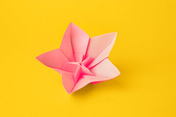 Canvas Print - Origami art. Handmade pink paper flower on yellow background, above view