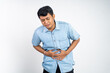 Portrait of young Asian man in painful holding stomach during stomachache on an isolated background