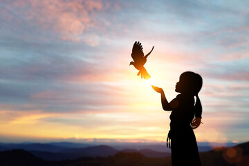 Fototapete - silhouette of bird flying out of Girl child hand on beautiful background.freedom concept ,International Working Women's Day