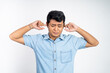 © Odua Images - portrait of young Asian man standing with two ears closed in an isolated background