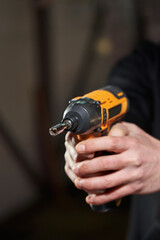 two men's hands tightly grip electric cordless impact wrench with small nut attachment