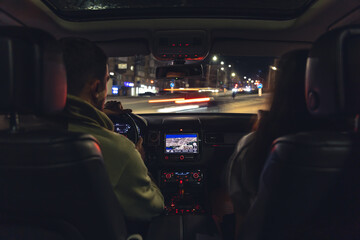 Wall Mural - Man and woman in a car at night, view from the car.