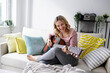 © Westend61 - Happy mature woman playing guitar on sofa at home