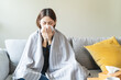 © Pormezz - Sick at home concept. Woman sneezing on the sofa in winter season.