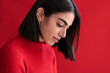 © Westend61 - Shy young woman looking down against red background