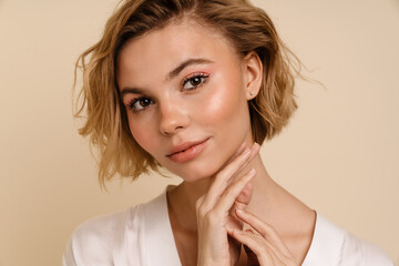 Young woman posing isolated over beige background