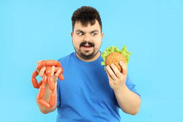 Concept of excess weight, fat guy with food on blue background