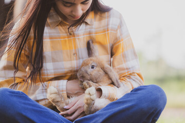 Wall Mural - relationships of cheerful rabbit and happy young human girl, Asian woman holding and carrying cute rabbit with tenderness and love. Friendship with cute easter bunny. Happy of Easter's Day