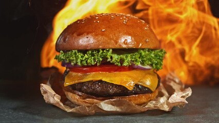 Wall Mural - Tasty cheeseburger, lying on vintage wooden cutting board with fire flames in background. Super Slow motion filmed on cinema camera at 1000 fps