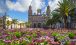 canvas print picture - Die Kathedrale Santa Ana in Las Palmas in der Frühlingssonne mit prächtigen magentafarbenen  Bornholmmargeriten als Vordergrundrahmen