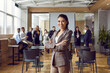 Leinwandbild Motiv Happy professional business teacher after corporate training class for team of workers. Beautiful young woman in suit jacket standing in office conference room, looking at camera and smiling