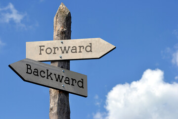 Forward or backward - wooden signpost with two arrows, sky with clouds