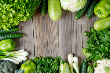Wall Mural - Frame of green raw vegetables on wooden background. Top view of healthy organic food. Copy space