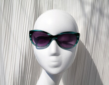 White Female Mannequin Wearing Blue Stylish Sunglasses In A Shopwindow. Fashionable Shades On Display In An Eyewear Store On A Lady Dummy Plastic Head