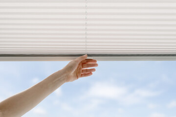 woman open cordless blind shutter on window