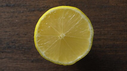 Wall Mural - Ripe half of yellow lemon citrus fruit on wooden background, close up, top view, rotate