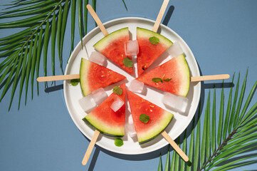 Wall Mural - Watermelon popsicles in a plate with ice cubes. Summer food background