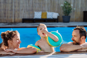 Wall Mural - Happy young family spending summer time together in their pool.