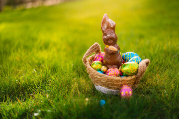 easter eggs in basket with easter bunny on top. chocolate rabbit with colorful decorated eggs in wic