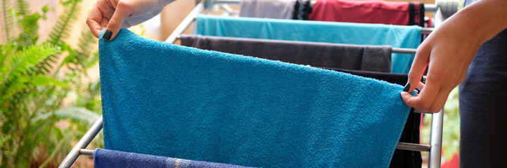 Woman hangs clean linen and towels on dryer at home closeup